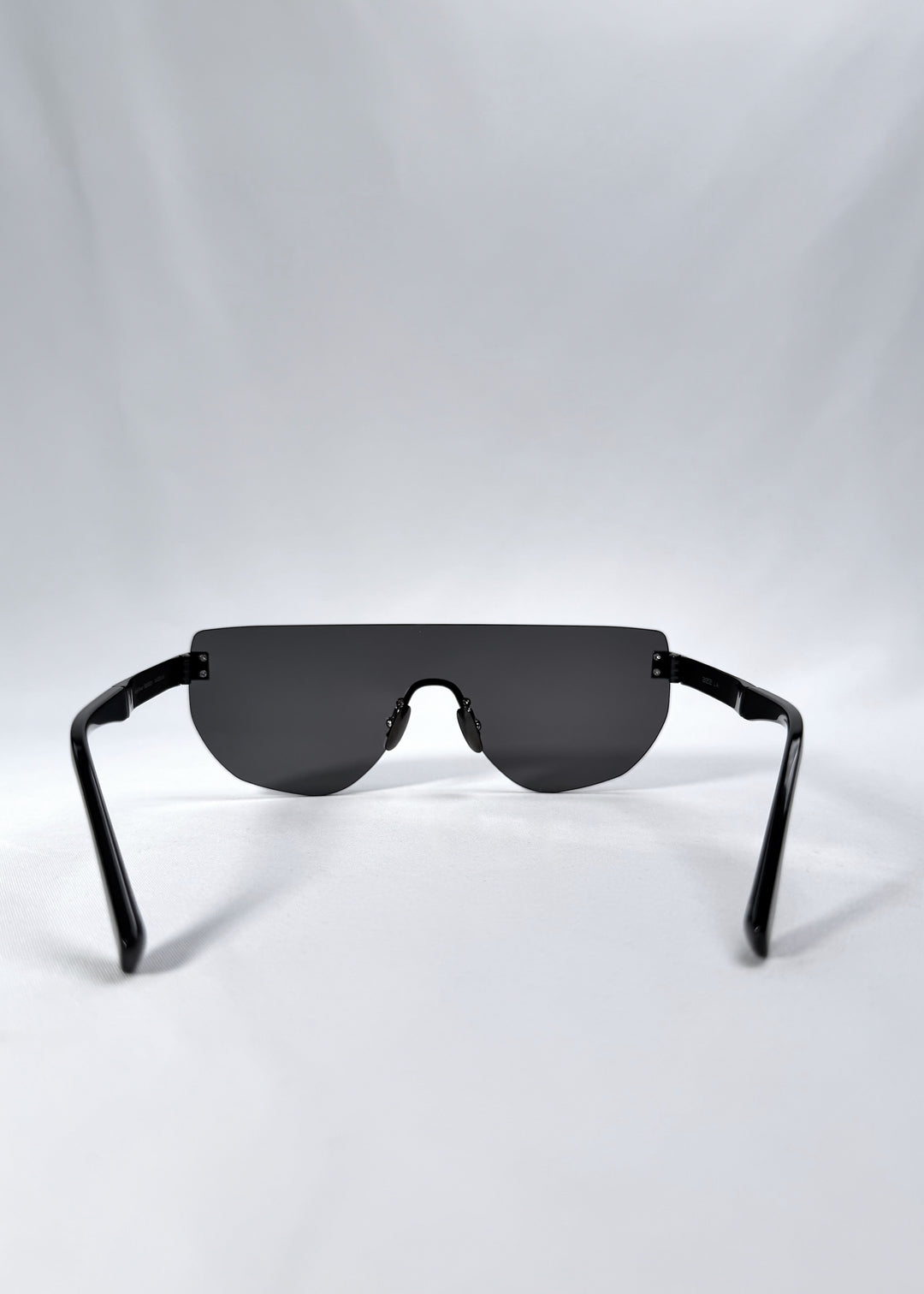 Back view of Aegis Field sunglasses in Obsidian Black, featuring one-piece titanium shield frame and smoky black lens, showing the inside frame and open temples.