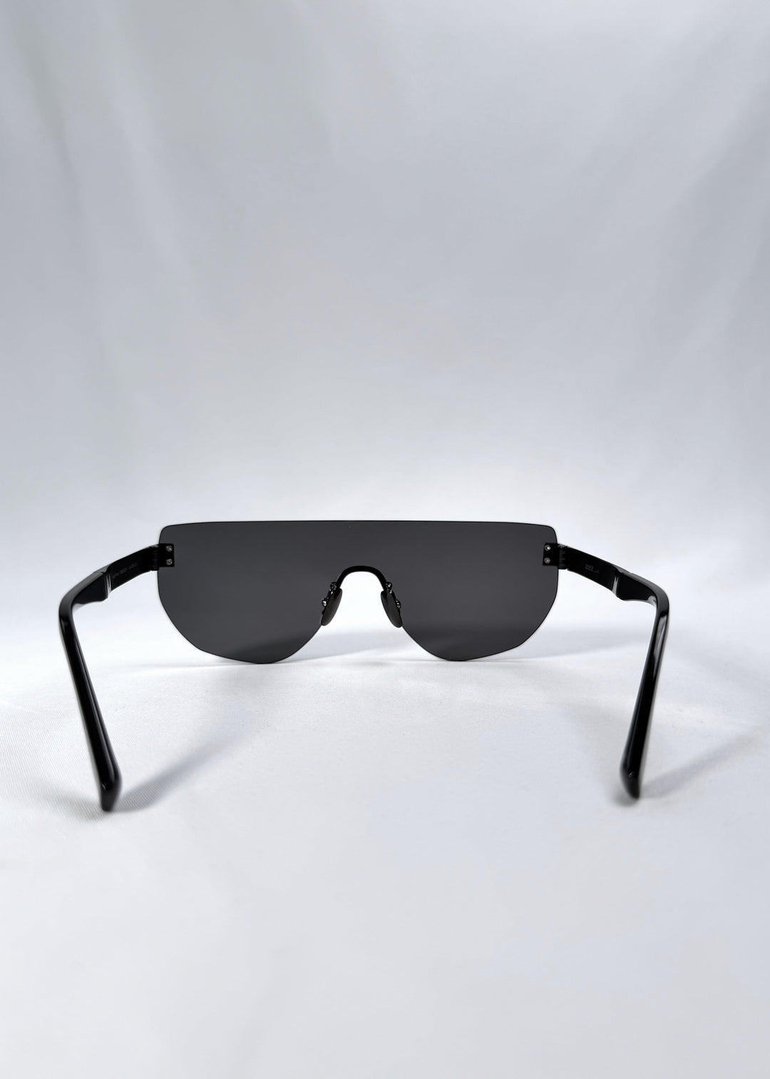 Back view of Aegis Field sunglasses in Obsidian Black, featuring one-piece titanium shield frame and smoky black lens, showing the inside frame and open temples. 