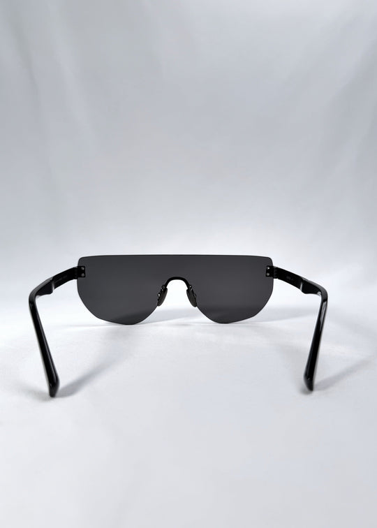 Back view of Aegis Field sunglasses in Obsidian Black, featuring one-piece titanium shield frame and smoky black lens, showing the inside frame and open temples. 
