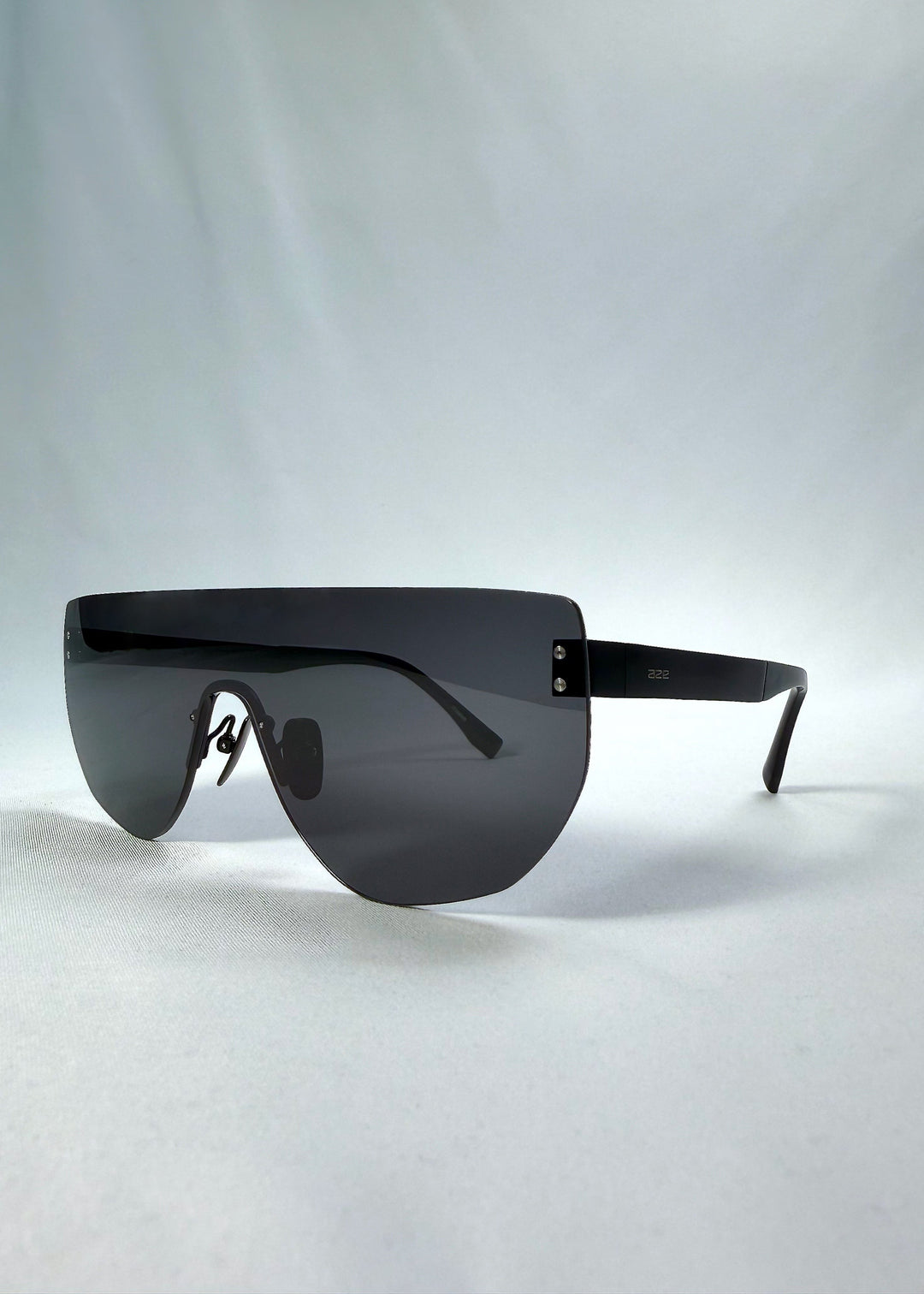 Three-quarter front view of Aegis Field sunglasses in Obsidian Black, featuring one-piece titanium shield frame and smoky black lens, showing the front shape and temple profile. 