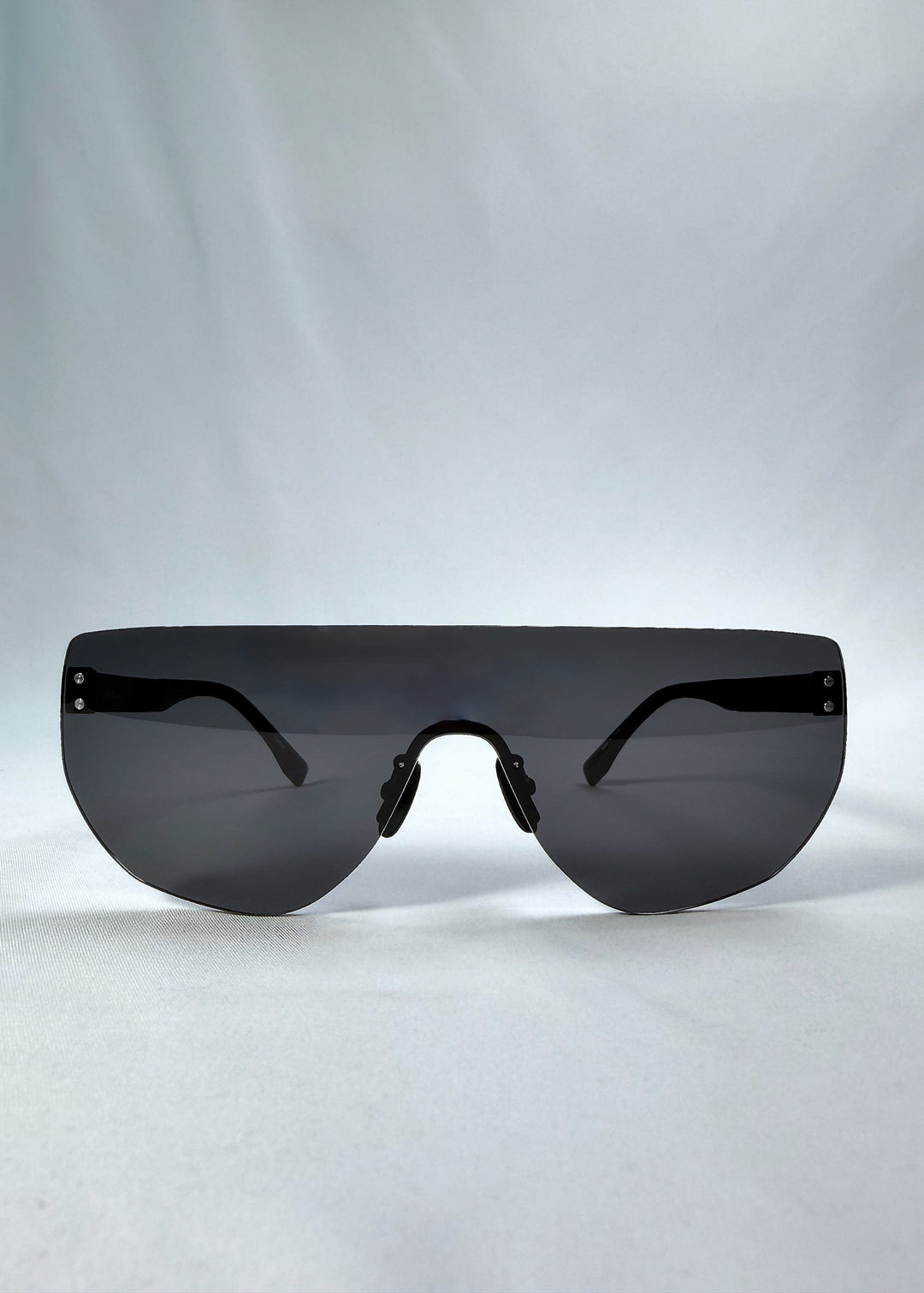 Front view of Aegis Field sunglasses in Obsidian Black, featuring one-piece titanium shield frame and smoky black lens, showing the full front silhouette. 