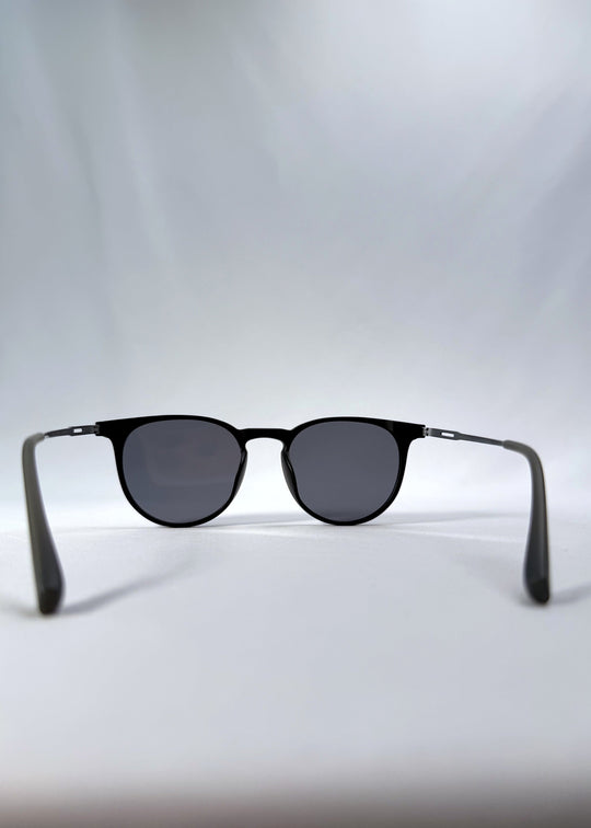 Back view of Altair sunglasses in Matte Black, featuring a minimal frame with titanium temples, rounded square lens shape, and polarized lenses, showing the inside frame and open temples. 
