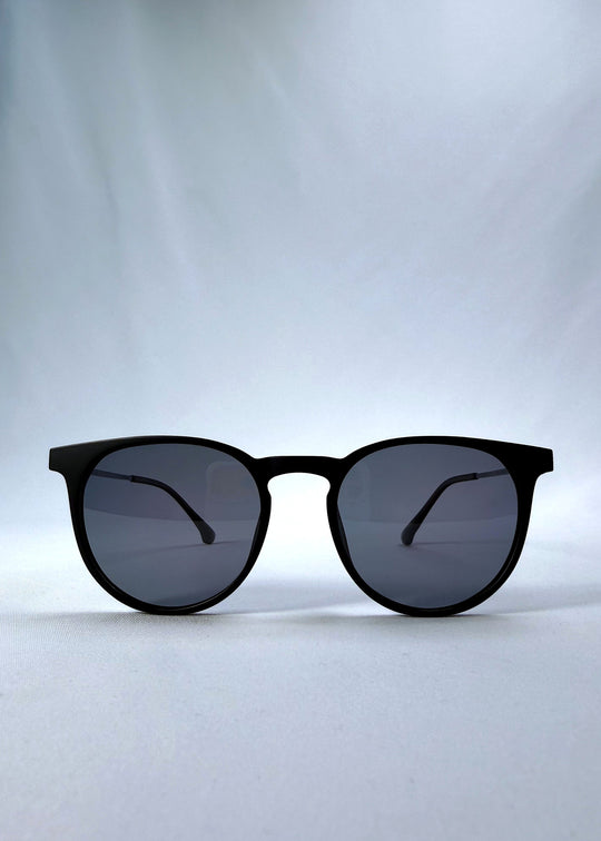 Front view of Altair sunglasses in Matte Black, featuring a minimal frame with titanium temples, rounded square lens shape, and polarized lenses, showing the full front silhouette. 