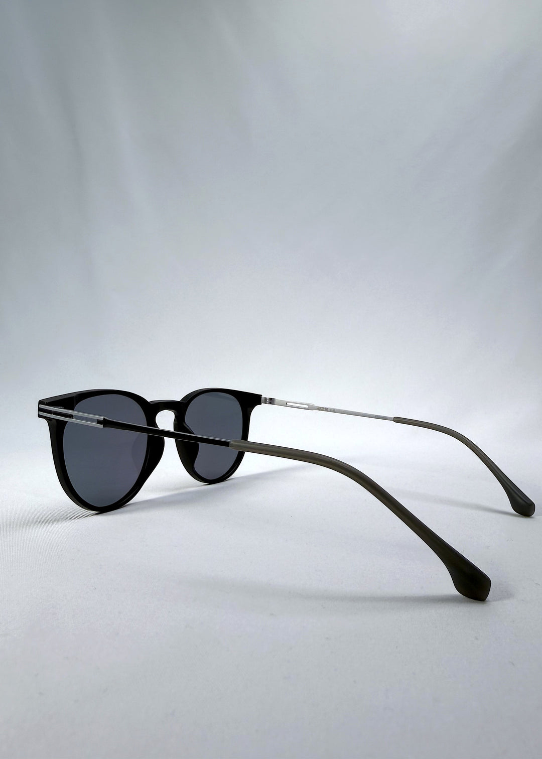 Side-angle view of Altair sunglasses in Matte Black, featuring minimal titanium frame, rounded square lens shape, and polarized lenses, showing the lens shape and temple profile.
