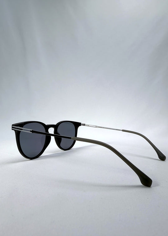 Side-angle view of Altair sunglasses in Matte Black, featuring minimal titanium frame, rounded square lens shape, and polarized lenses, showing the lens shape and temple profile.