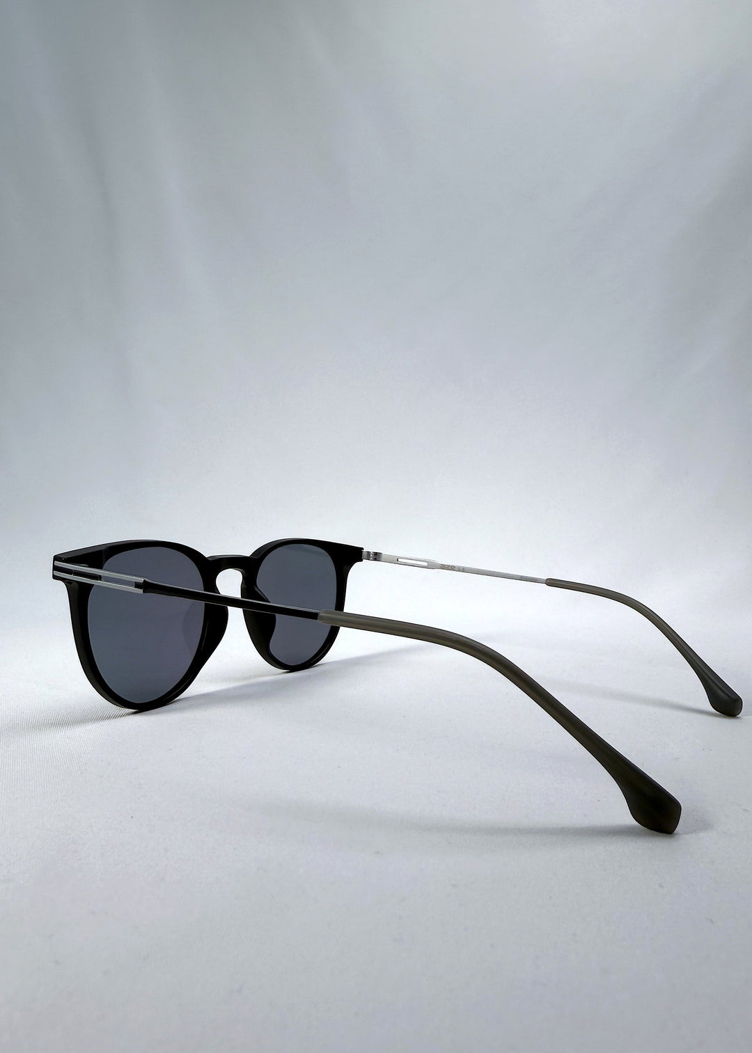 Side-angle view of Altair sunglasses in Matte Black, featuring a minimal frame with titanium temples, rounded square lens shape, and polarized lenses, showing the lens shape and temple profile. 