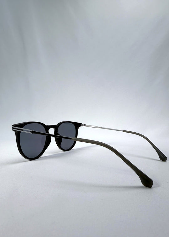Side-angle view of Altair sunglasses in Matte Black, featuring a minimal frame with titanium temples, rounded square lens shape, and polarized lenses, showing the lens shape and temple profile. 
