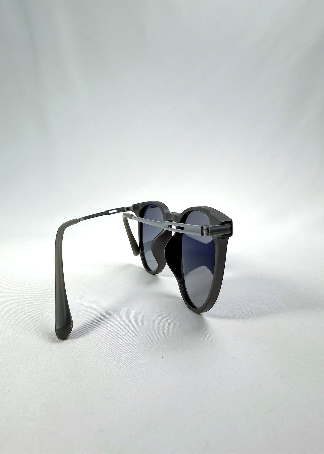Back-angle view of Altair sunglasses in Matte Gray, featuring minimal titanium frame, rounded square lens shape, and polarized lenses, showing the back structure and temple alignment.