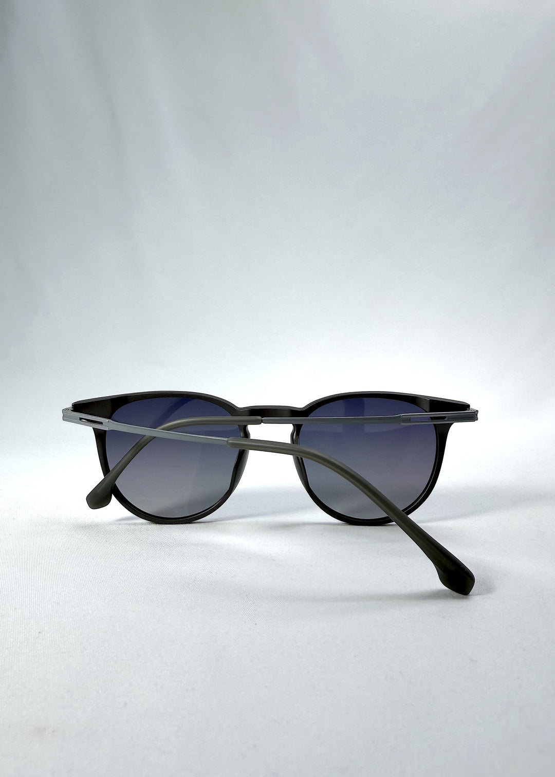 Folded view of Altair sunglasses in Matte Gray, featuring a minimal frame with titanium temples, rounded square lens shape, and polarized lenses, showing the folded temples and frame profile. 