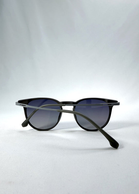 Folded view of Altair sunglasses in Matte Gray, featuring a minimal frame with titanium temples, rounded square lens shape, and polarized lenses, showing the folded temples and frame profile. 