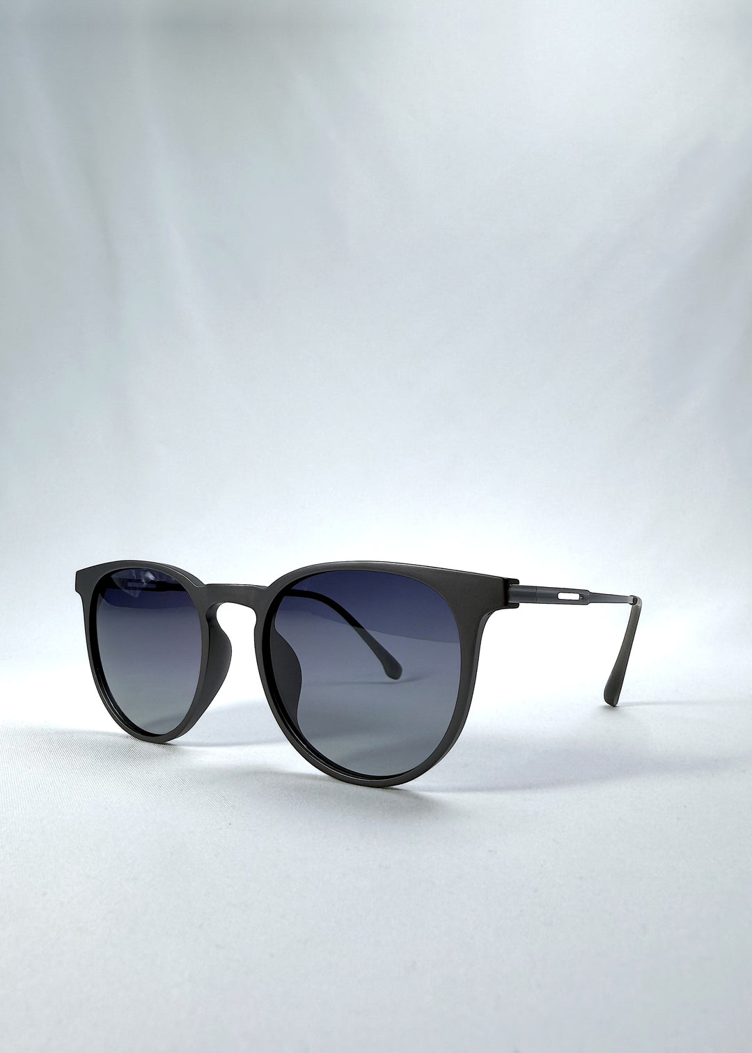 Three-quarter front view of Altair sunglasses in Matte Gray, featuring minimal titanium frame, rounded square lens shape, and polarized lenses, showing the front shape and temple profile.