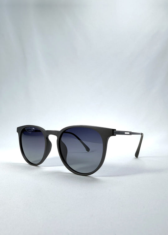 Three-quarter front view of Altair sunglasses in Matte Gray, featuring minimal titanium frame, rounded square lens shape, and polarized lenses, showing the front shape and temple profile.