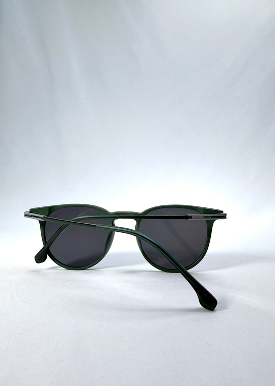 Folded view of Altair sunglasses in Matte Green, featuring a minimal frame with titanium temples, rounded square lens shape, and polarized lenses, showing the folded temples and frame profile. 