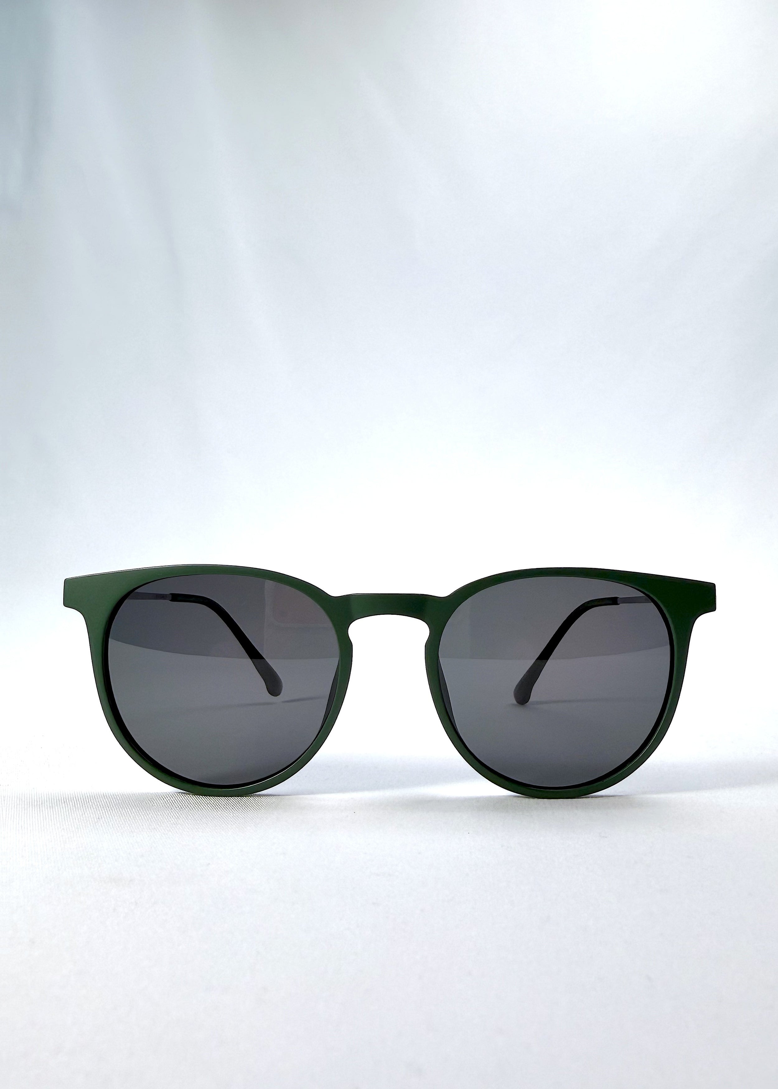 Front view of Altair sunglasses in Matte Green, featuring minimal titanium frame, rounded square lens shape, and polarized lenses, showing the full front silhouette.