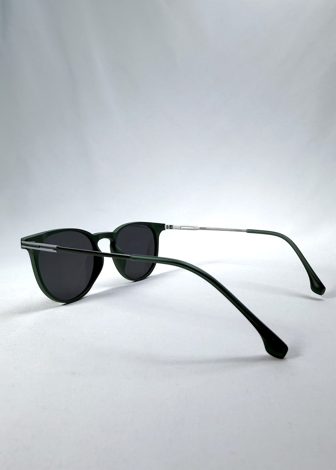 Side-angle view of Altair sunglasses in Matte Green, featuring minimal titanium frame, rounded square lens shape, and polarized lenses, showing the lens shape and temple profile.