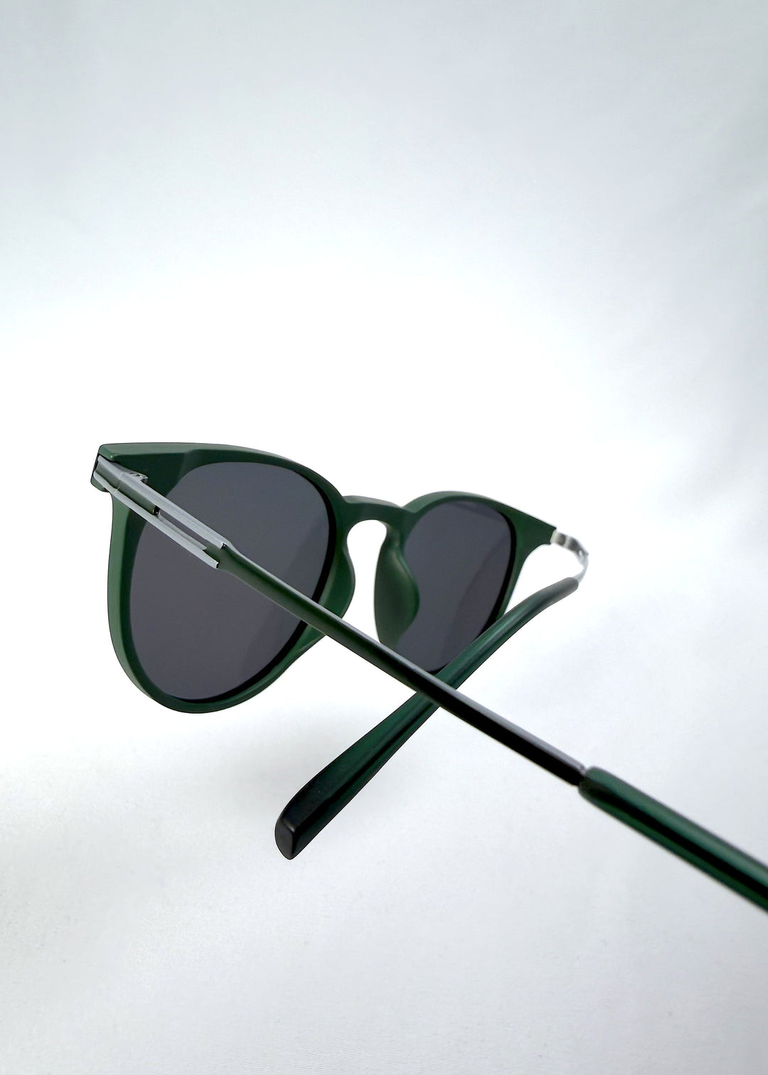 Close-up temple detail view of Altair sunglasses in Matte Green, featuring a minimal frame with titanium temples, rounded square lens shape, and polarized lenses, showing the temple arm and hinge area. 