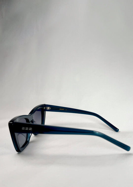 Side view of Aquila Blue sunglasses, showing the transparent blue gradient frame and temple profile. 