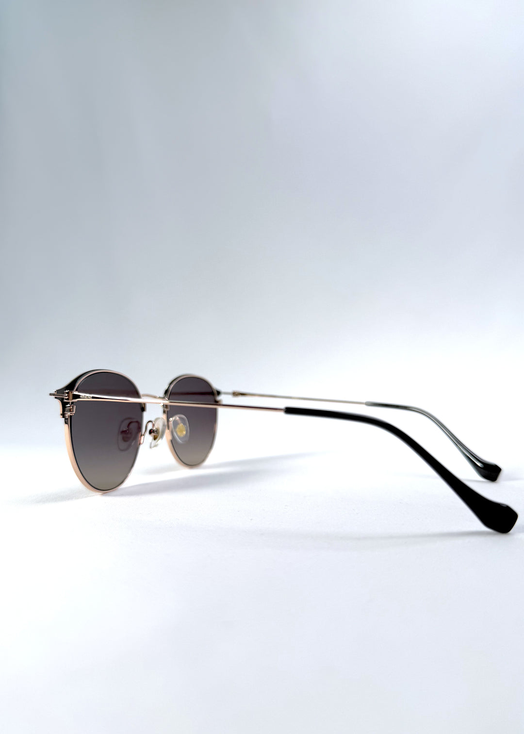 Back-angle view of AZE Aster Line sunglasses in Duskgold, featuring a gold-tone rounded frame and plum-to-amber gradient lenses, showing the rear frame structure and temple alignment.