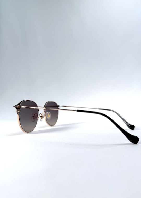 Back-angle view of AZE Aster Line sunglasses in Duskgold, featuring a gold-tone rounded frame and plum-to-amber gradient lenses, showing the rear frame structure and temple alignment.