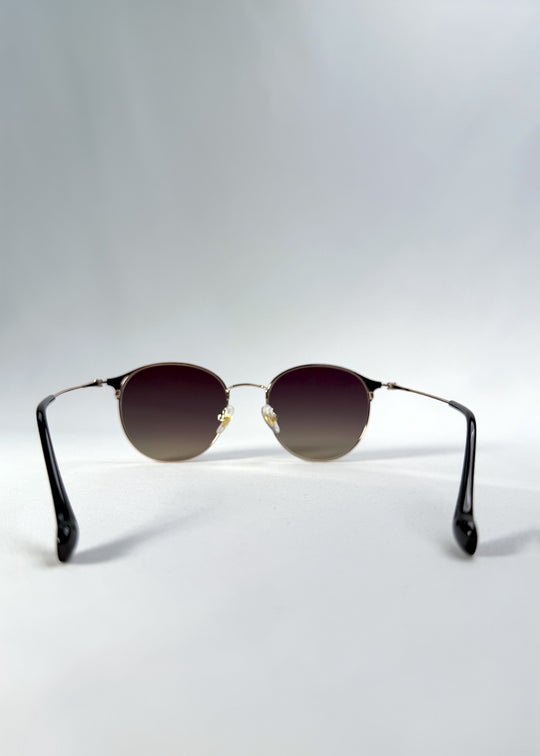 Back view of AZE Aster Line sunglasses in Duskgold, featuring a gold-tone rounded frame and plum-to-amber gradient lenses, showing the inner frame and open temples.