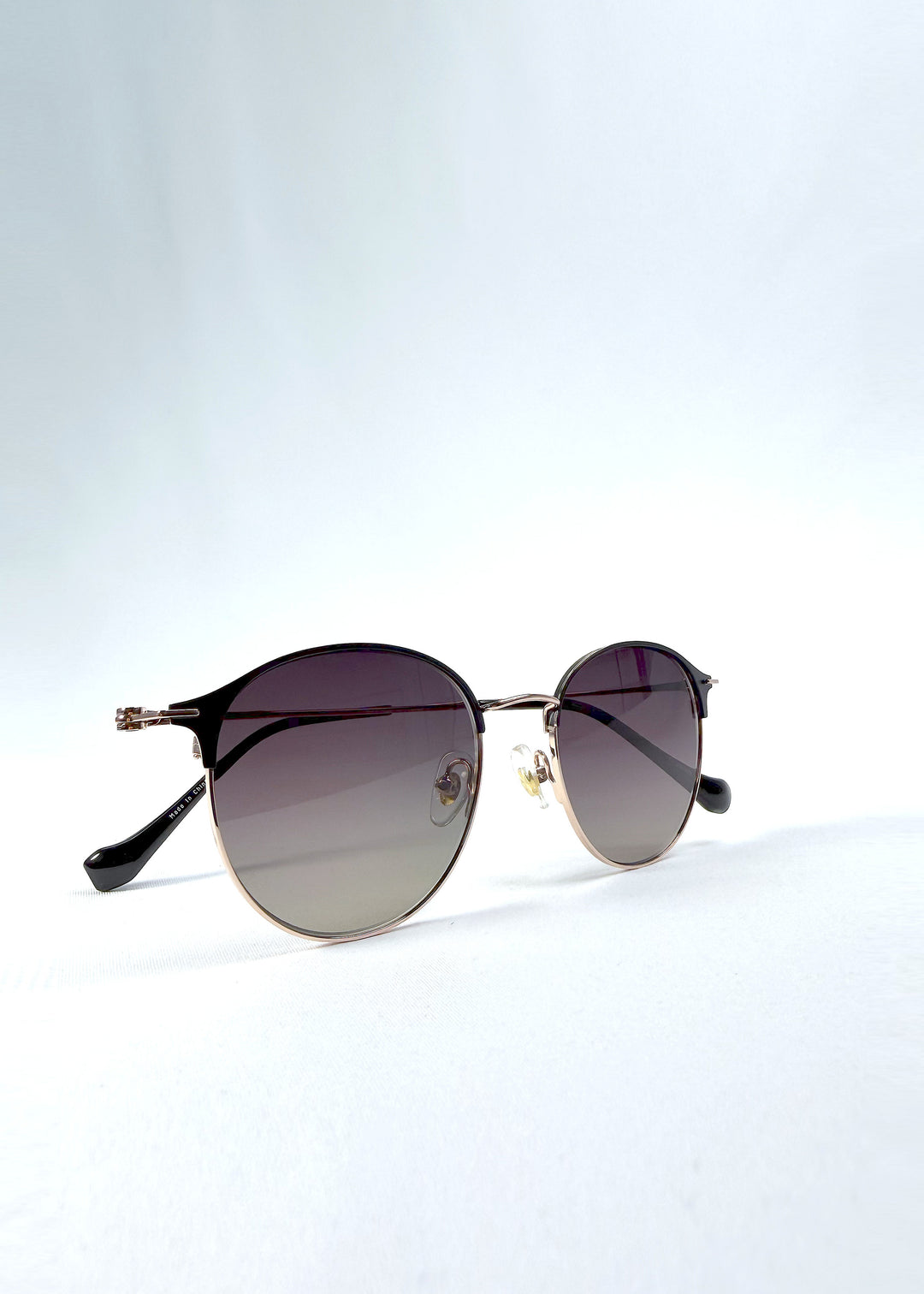 Folded view of AZE Aster Line sunglasses in Duskgold, featuring a gold-tone rounded frame and plum-to-amber gradient lenses, showing the folded temples and frame profile.