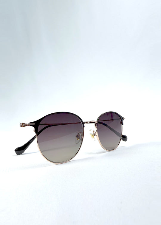 Folded view of AZE Aster Line sunglasses in Duskgold, featuring a gold-tone rounded frame and plum-to-amber gradient lenses, showing the folded temples and frame profile.