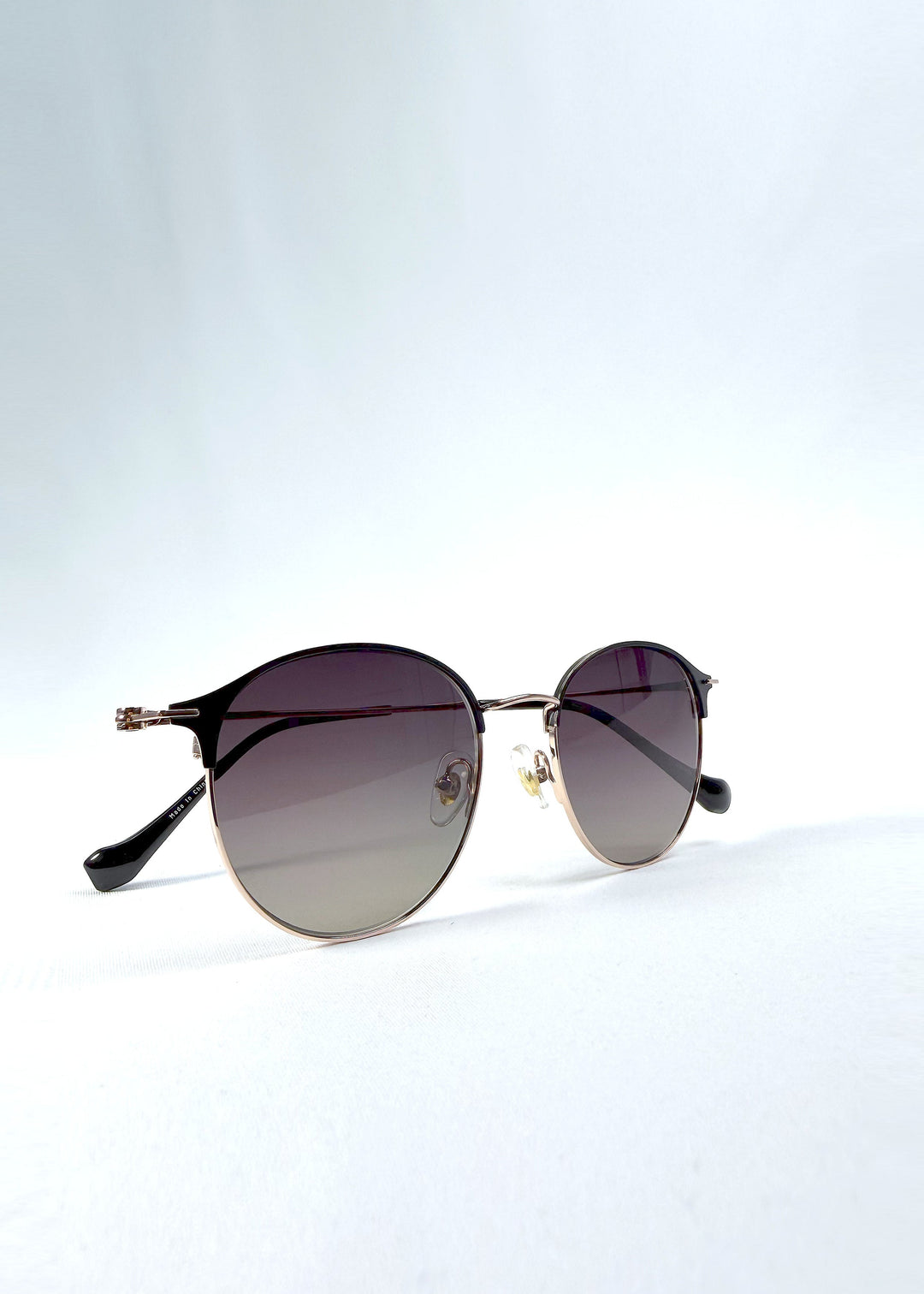 Folded view of AZE Aster Line sunglasses in Duskgold, featuring a gold-tone rounded frame and plum-to-amber gradient lenses, showing the folded temples and frame profile. 