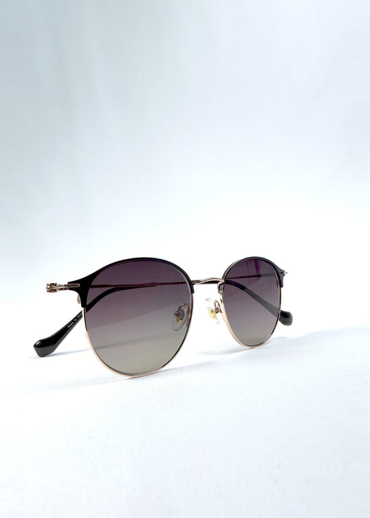 Folded view of AZE Aster Line sunglasses in Duskgold, featuring a gold-tone rounded frame and plum-to-amber gradient lenses, showing the folded temples and frame profile. 