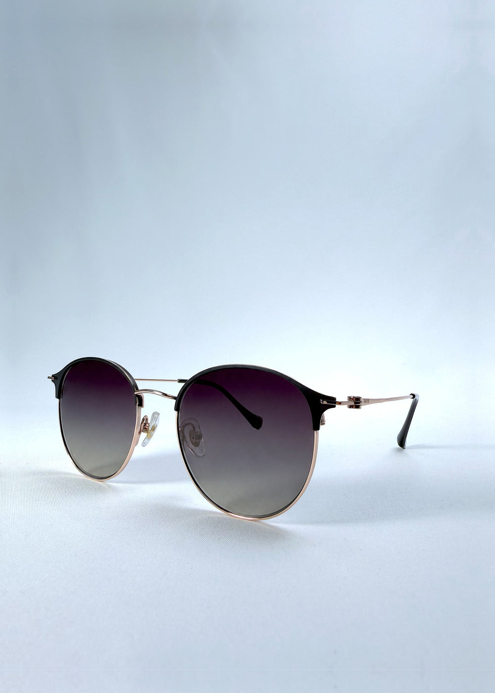 Three-quarter front view of AZE Aster Line sunglasses in Duskgold, featuring a gold-tone rounded frame and plum-to-amber gradient lenses, showing the frame shape and temple profile.