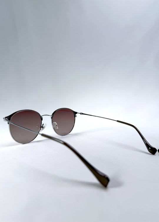 Back-angle view of AZE Aster Line sunglasses in Mocha Dusk, featuring a silver-tone rounded frame and taupe gradient lenses, showing the rear frame structure and temple alignment. 