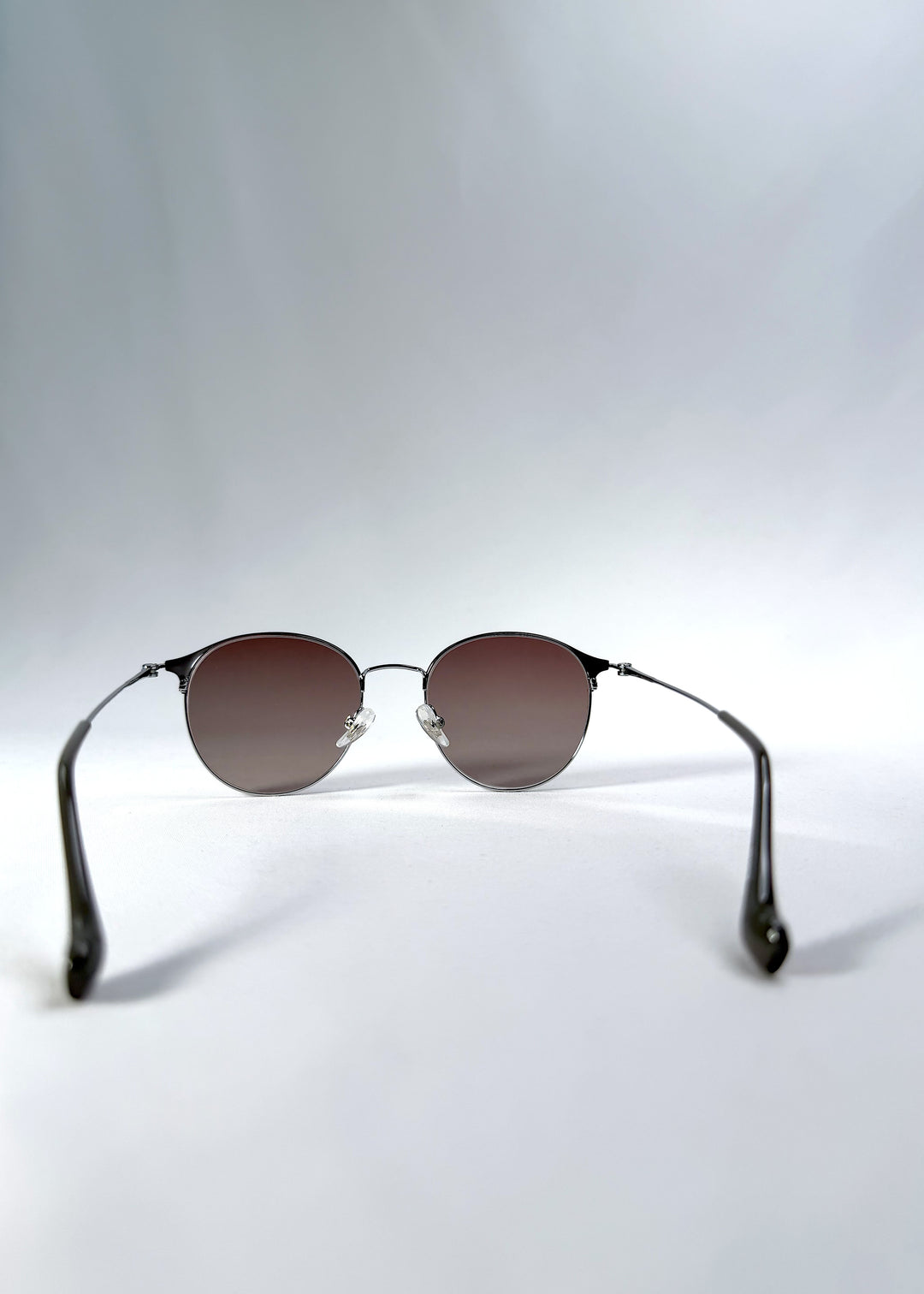 Back view of AZE Aster Line sunglasses in Mocha Dusk, featuring a silver-tone rounded frame and taupe gradient lenses, showing the inner frame and open temples.