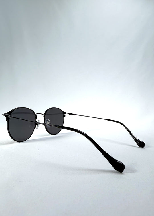 Back-angle view of AZE Aster Line sunglasses in Obsidian Black, featuring a dark geometric round frame and smoky gray lenses, showing the rear frame structure and temple alignment.