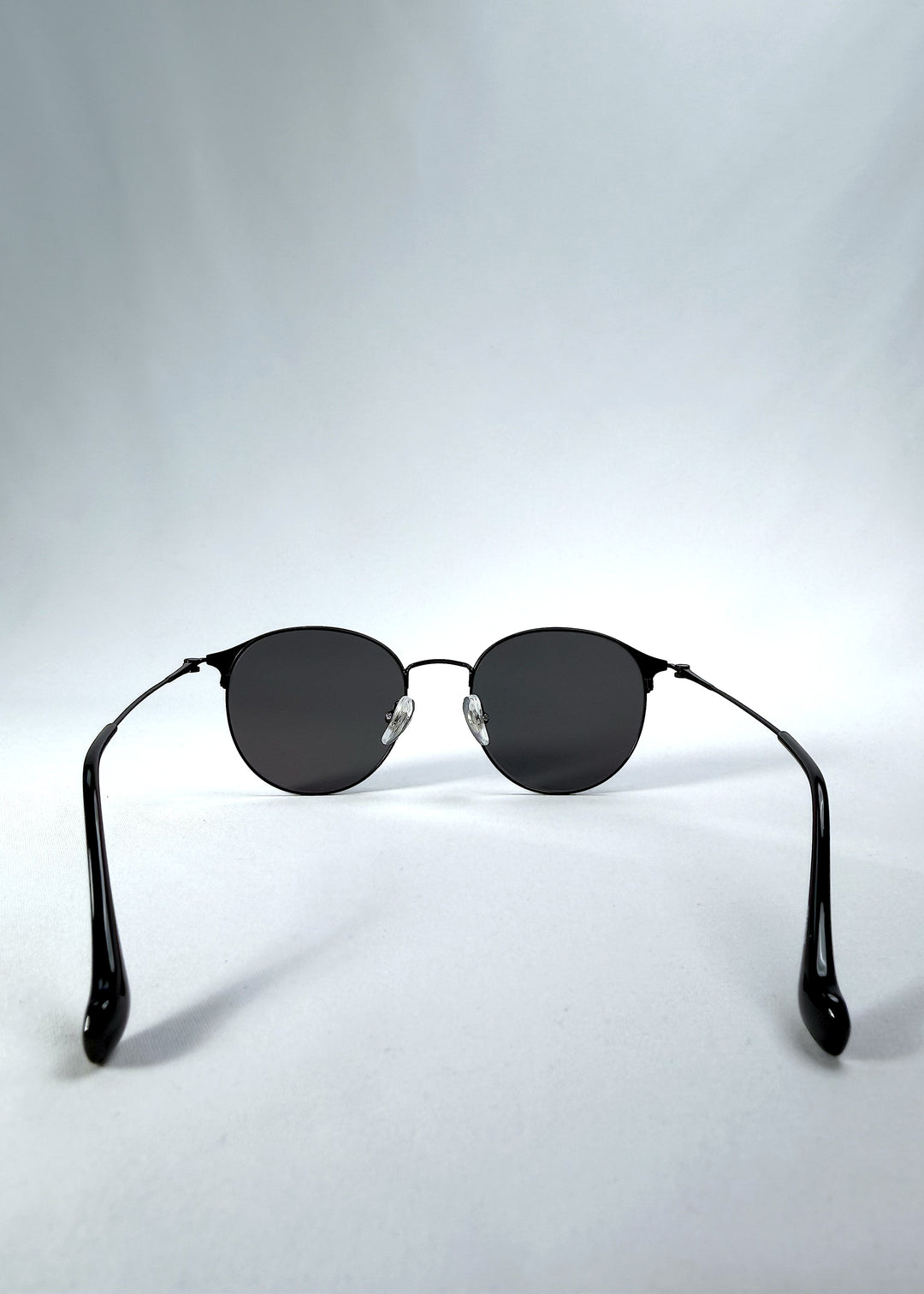 Back view of AZE Aster Line sunglasses in Obsidian Black, featuring a dark geometric round frame and smoky gray lenses, showing the inner frame and open temples.