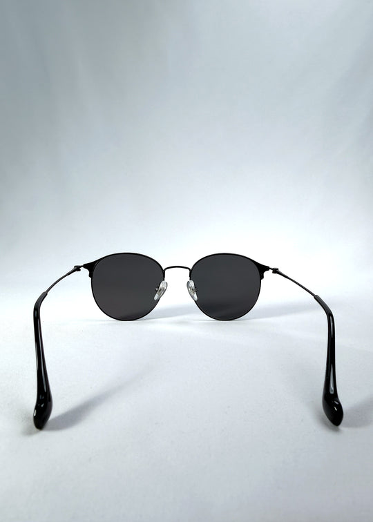 Back view of AZE Aster Line sunglasses in Obsidian Black, featuring a dark geometric round frame and smoky gray lenses, showing the inner frame and open temples.