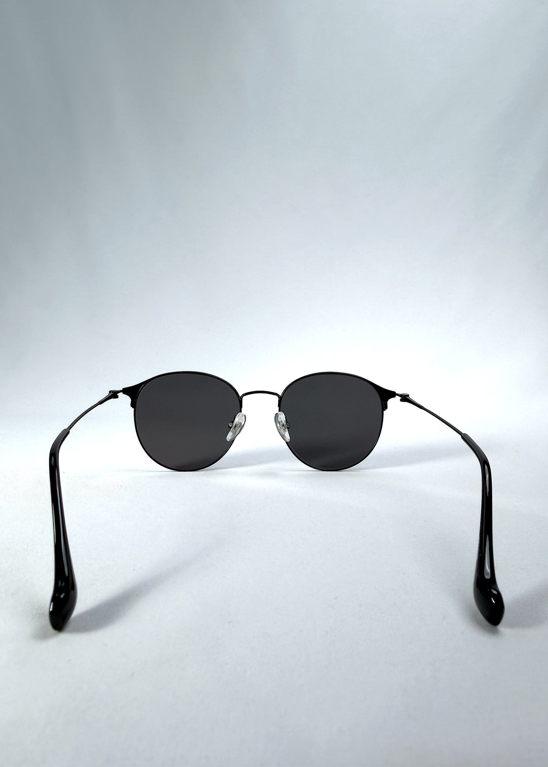 Back view of AZE Aster Line sunglasses in Obsidian Black, featuring a dark geometric round frame and smoky gray lenses, showing the inner frame and open temples. 