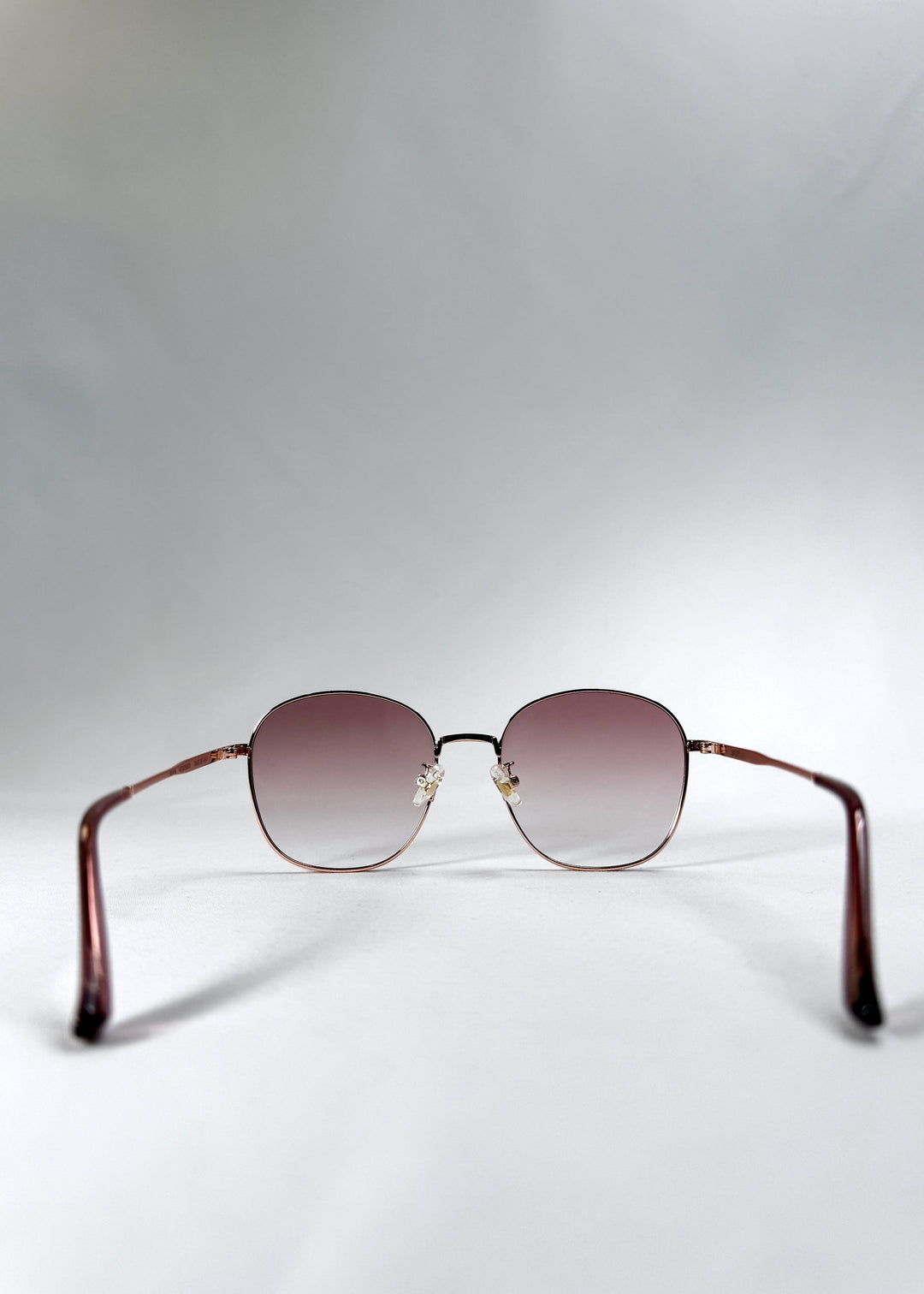 Back view of Astris – Rosé Dawn sunglasses with clear nose pads and rose-toned temples extending smoothly to the back. 