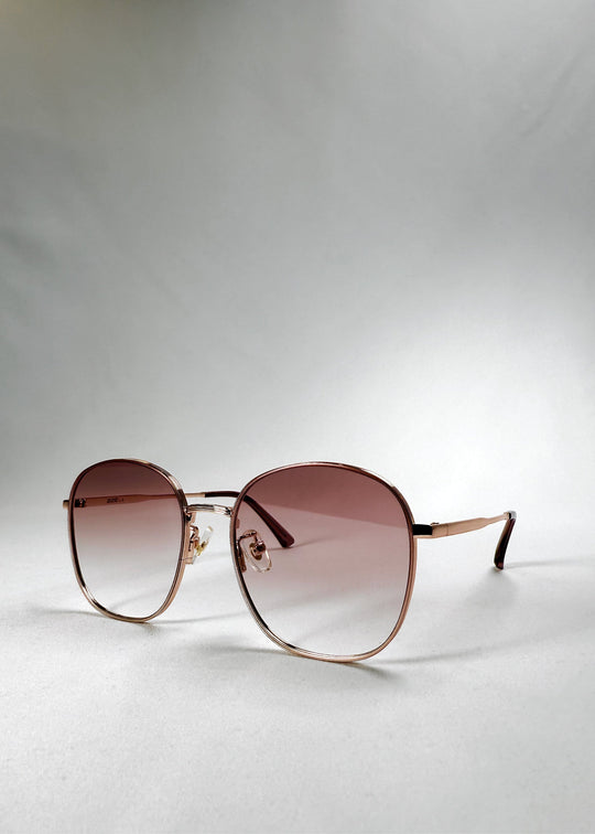 Angled front view of Astris – Rosé Dawn showing the oversized geometrical frame and gradient lenses that enhance facial lift. 
