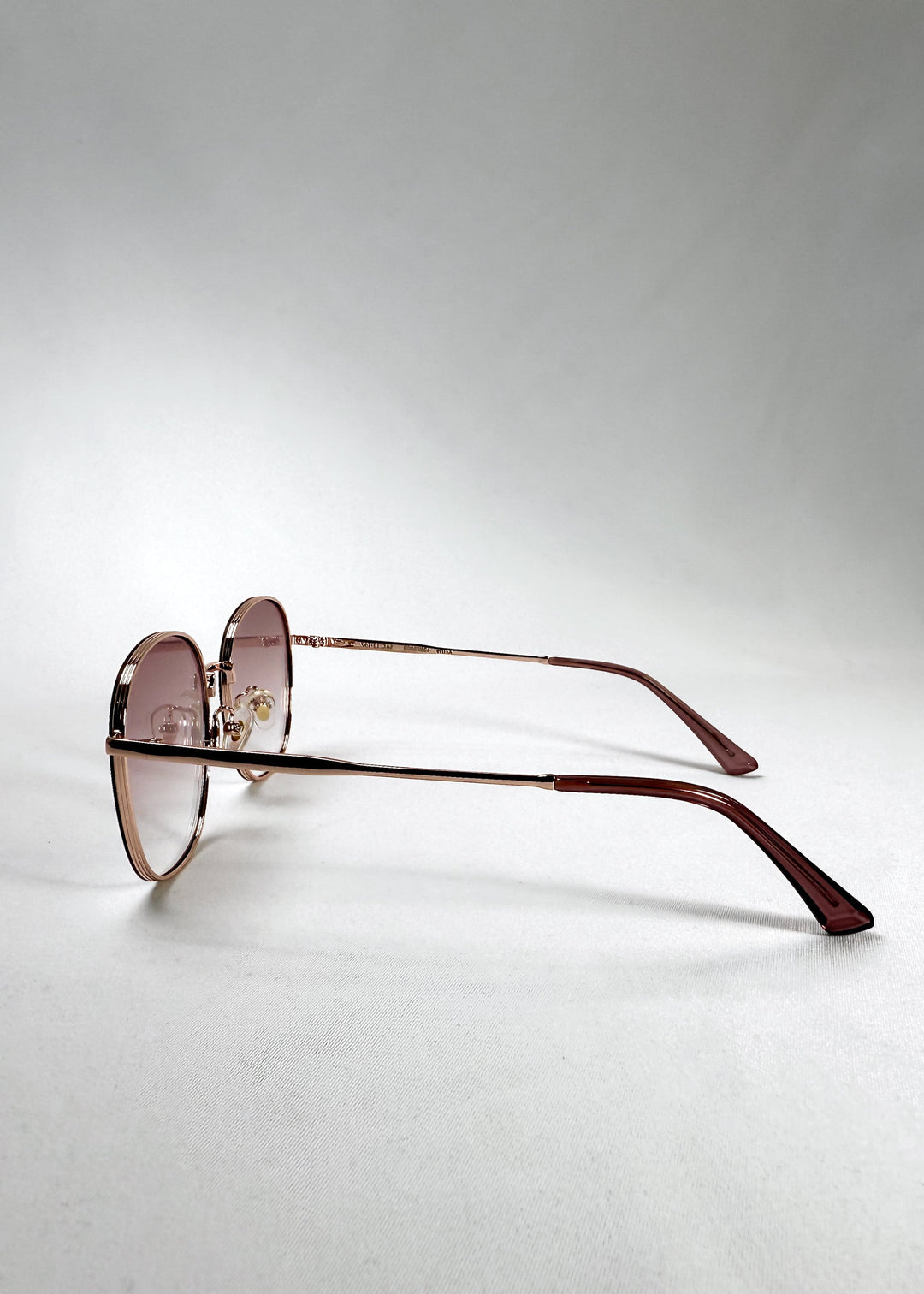 Side view of Astris – Rosé Dawn featuring slim stainless steel arms with a light rose finish and curved acetate temple tips. 