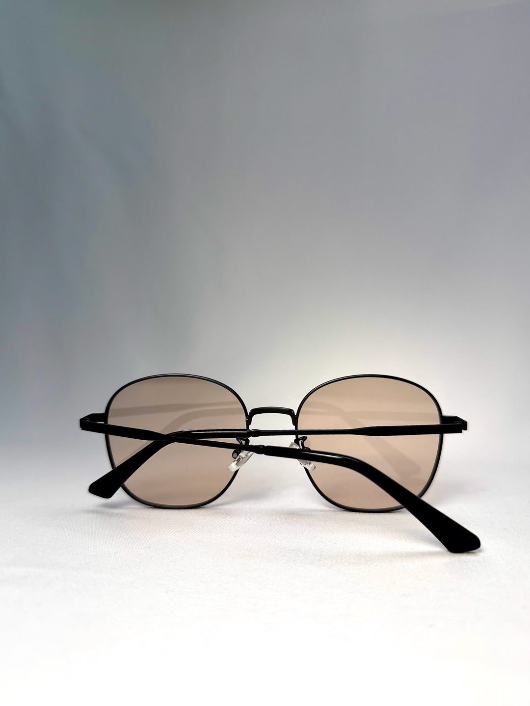 Astris sunglasses in Satin Bronze, front folded view showing the dark bronze frame and warm tea lenses. 