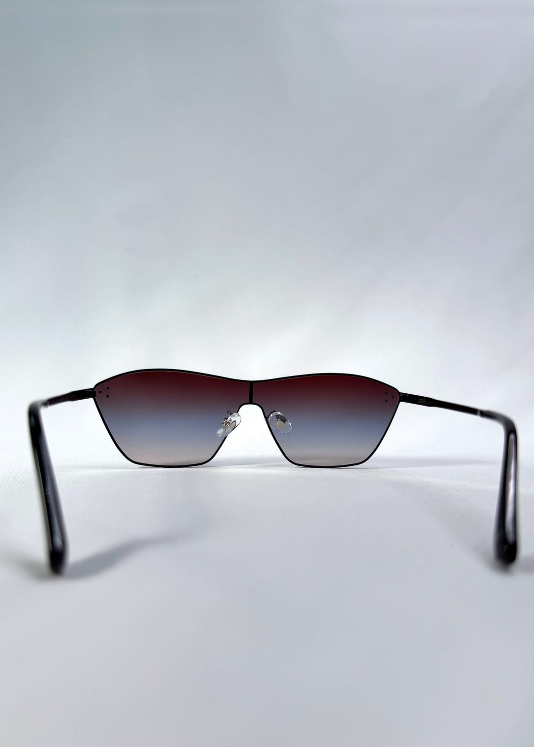 Back view of Atlas Shield sunglasses in Midnight Eclipse, featuring one-piece shield lens, slim metal frame, and dark gradient tint, showing the inside frame and open temples. 