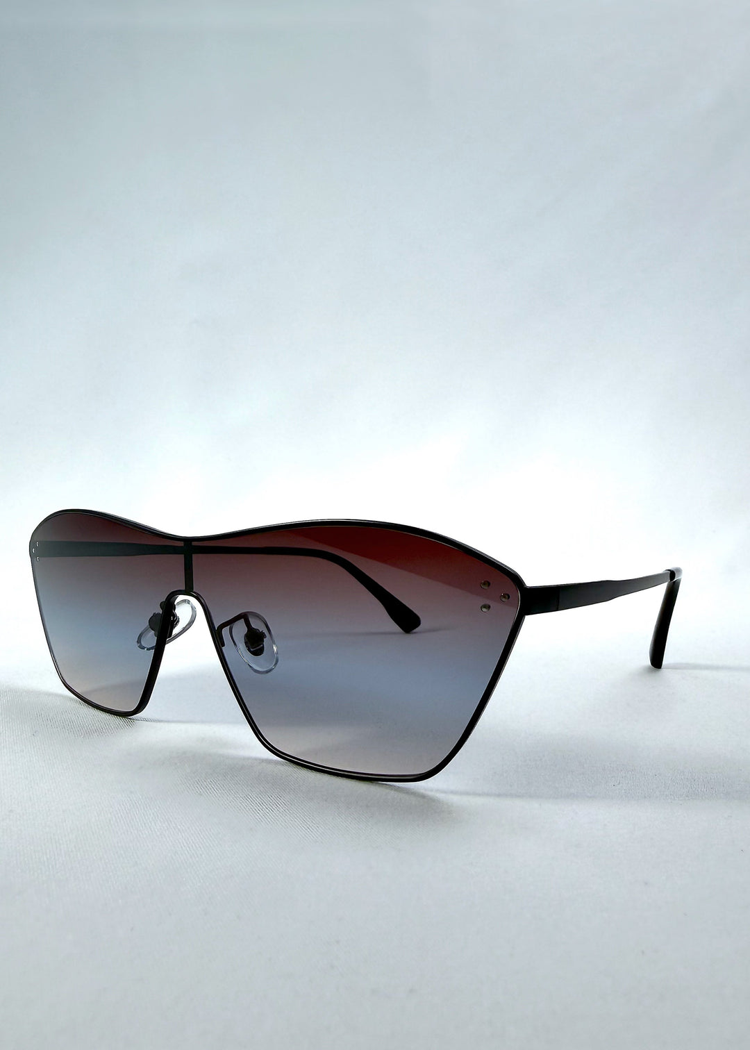 Three-quarter front view of Atlas Shield sunglasses in Midnight Eclipse, featuring one-piece shield lens, slim metal frame, and dark gradient tint, showing the front shape and temple profile. 