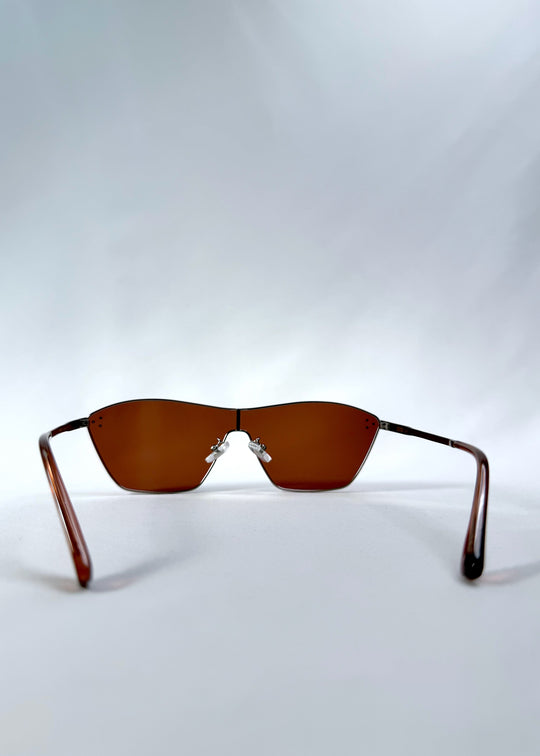 Back view of Atlas Shield sunglasses in Ruby Smoke, featuring one-piece shield lens, slim metal frame, and wine-red tint, showing the inside frame and open temples.