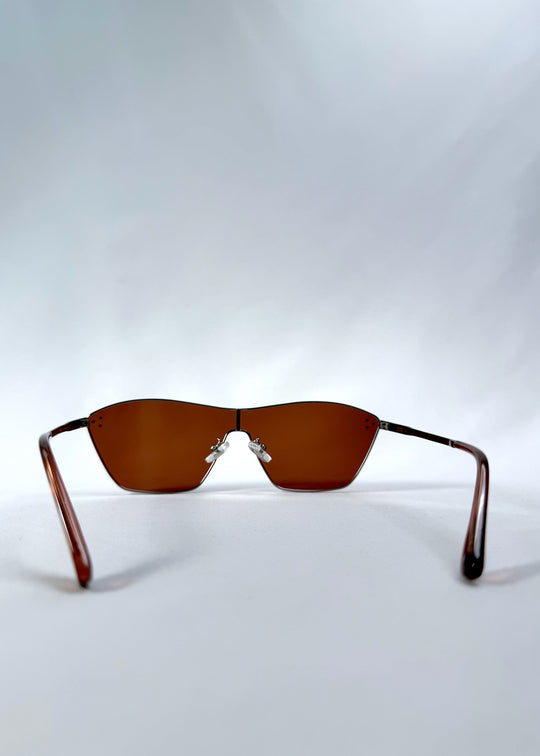 Back view of Atlas Shield sunglasses in Ruby Smoke, featuring one-piece shield lens, slim metal frame, and wine-red tint, showing the inside frame and open temples. 