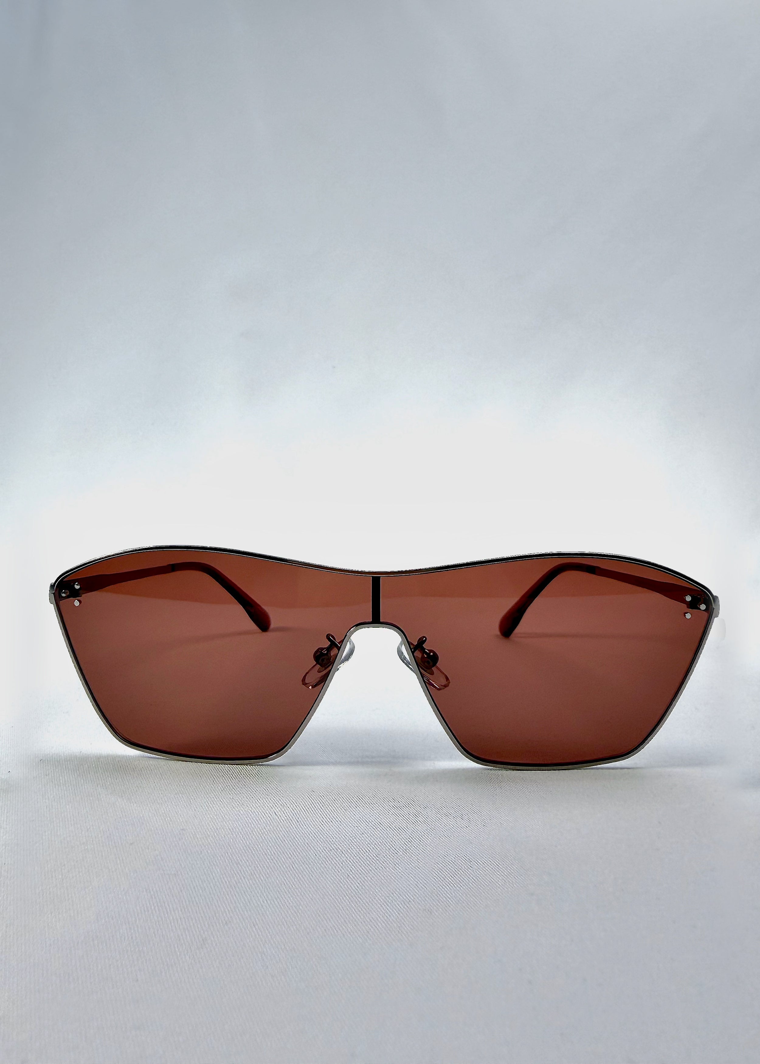 Front view of Atlas Shield sunglasses in Ruby Smoke, featuring one-piece shield lens, slim metal frame, and wine-red tint, showing the full front silhouette.