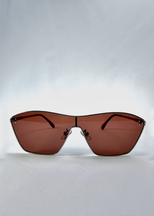 Front view of Atlas Shield sunglasses in Ruby Smoke, featuring one-piece shield lens, slim metal frame, and wine-red tint, showing the full front silhouette. 