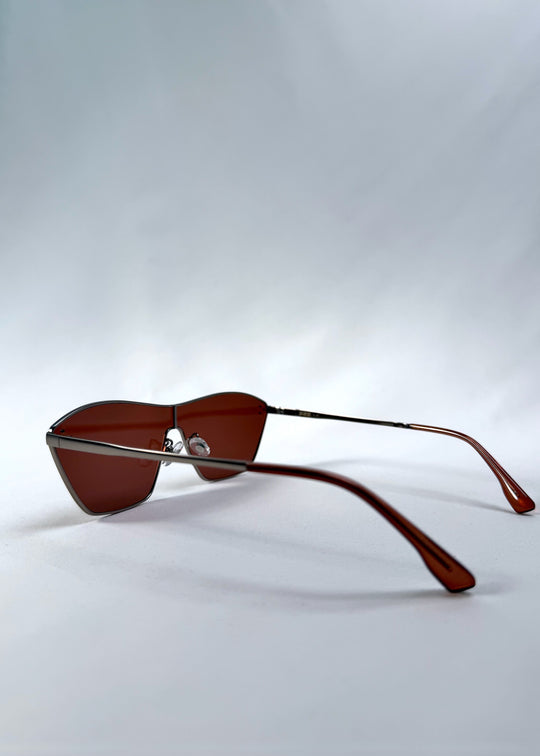 Side view of Atlas Shield sunglasses in Ruby Smoke, featuring one-piece shield lens, slim metal frame, and wine-red tint, showing the lens shape and temple profile.