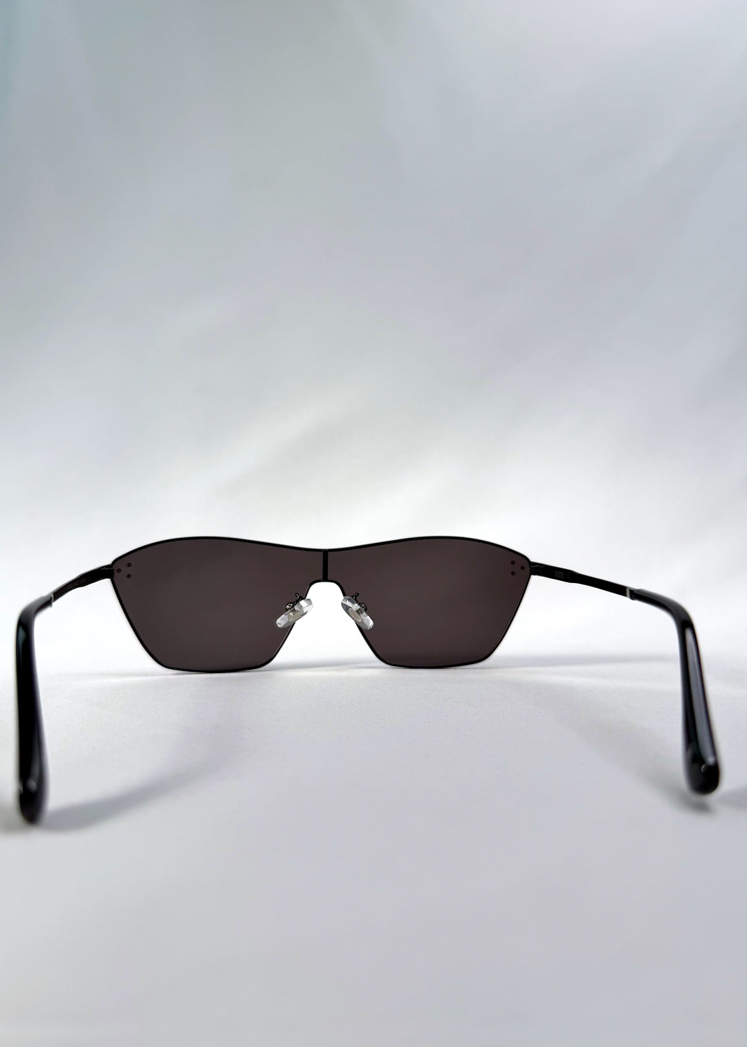 Back view of Atlas Shield sunglasses in Slate Smoke, featuring one-piece shield lens, slim metal frame, and full grey tint, showing the inside frame and open temples.