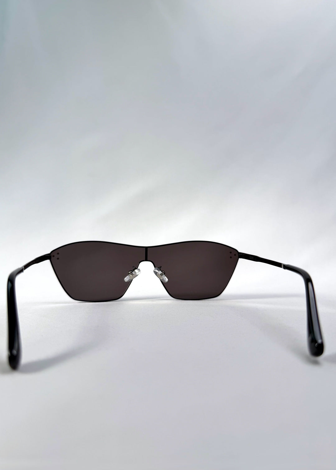 Back view of Atlas Shield sunglasses in Slate Smoke, featuring one-piece shield lens, slim metal frame, and full grey tint, showing the inside frame and open temples. 