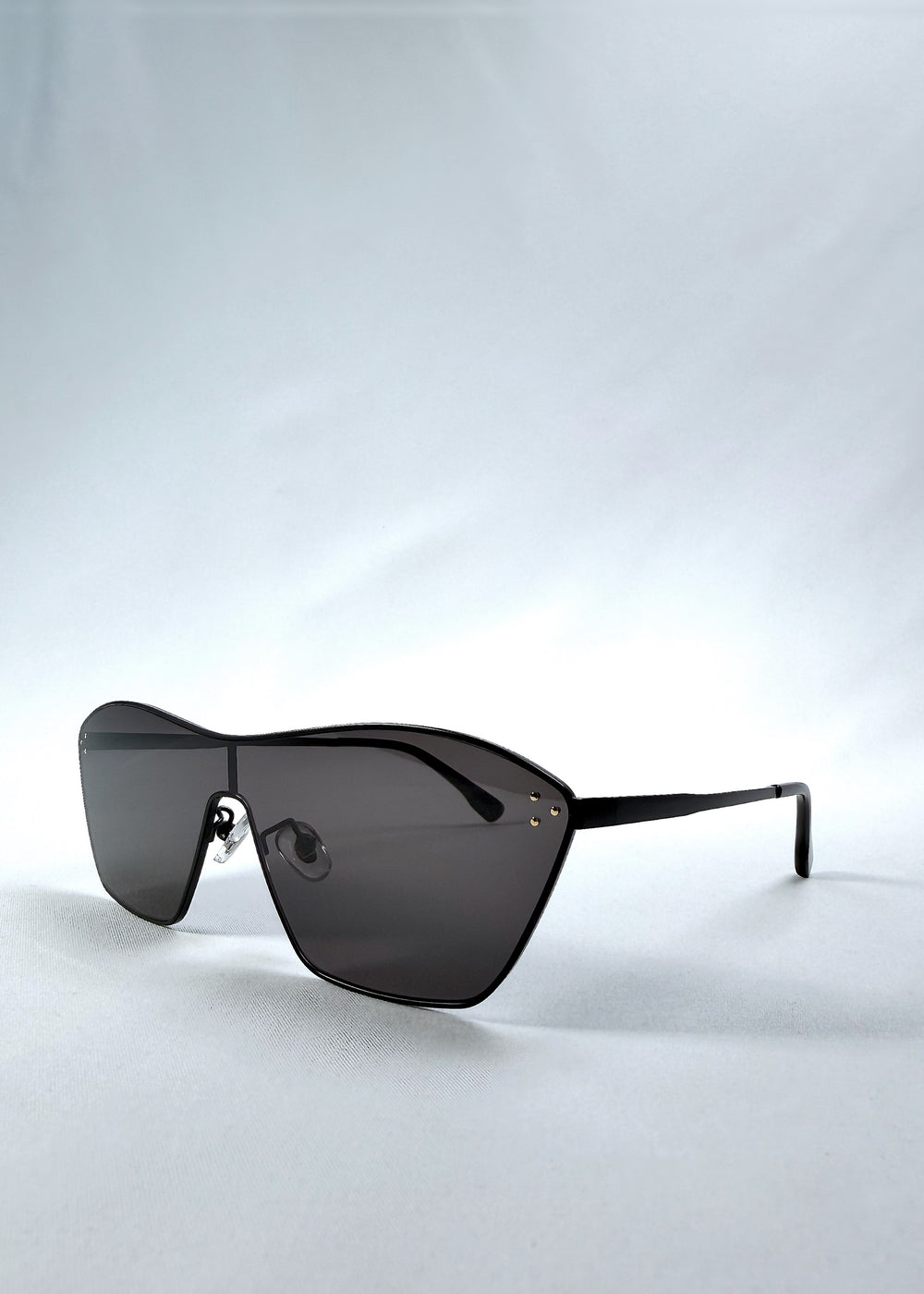 Three-quarter front view of Atlas Shield sunglasses in Slate Smoke, featuring one-piece shield lens, slim metal frame, and full grey tint, showing the front shape and temple profile.