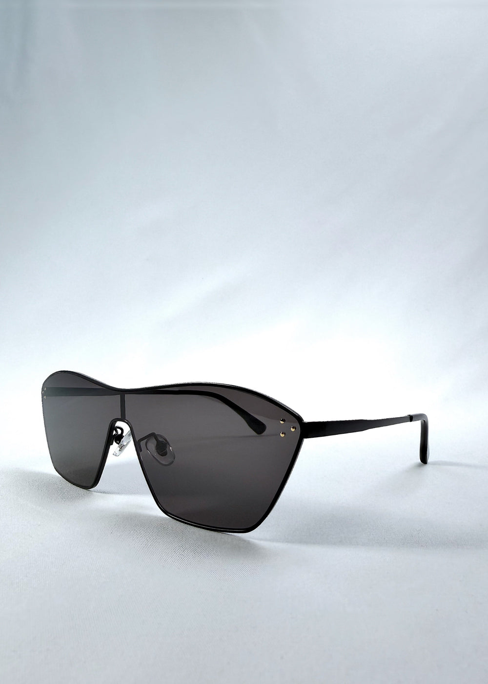 Three-quarter front view of Atlas Shield sunglasses in Slate Smoke, featuring one-piece shield lens, slim metal frame, and full grey tint, showing the front shape and temple profile. #color_slate-smoke